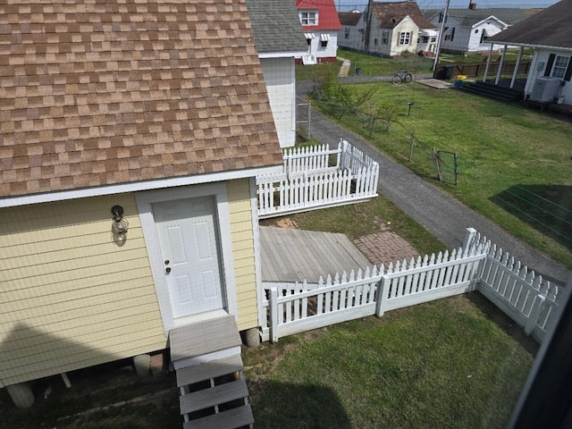 entrance to property featuring fence, a shingled roof, and a deck
