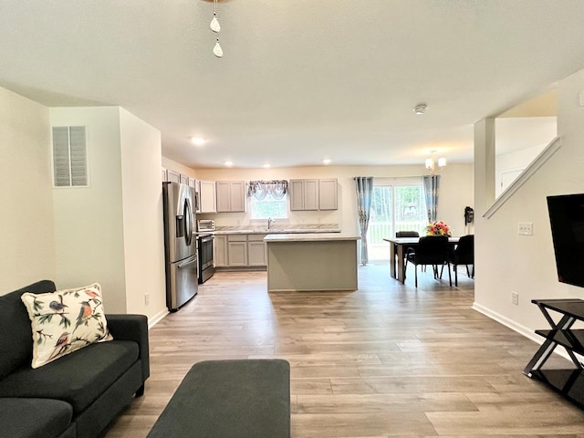 living room with a chandelier, light hardwood / wood-style flooring, and sink