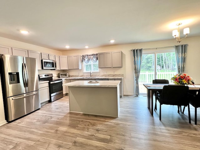 kitchen featuring pendant lighting, a center island, light hardwood / wood-style floors, stainless steel appliances, and a chandelier