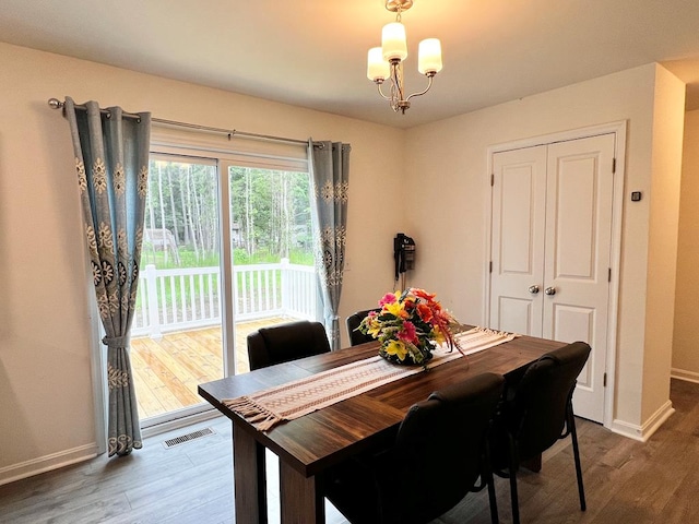 dining space with hardwood / wood-style flooring and a notable chandelier