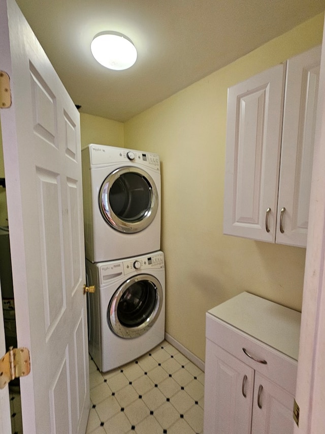 laundry area featuring cabinets and stacked washer and clothes dryer