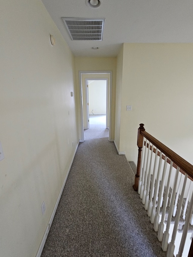 hall featuring visible vents, light carpet, baseboards, and an upstairs landing