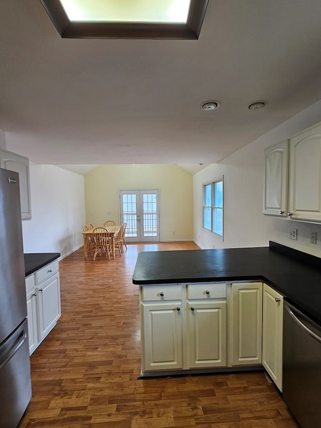 kitchen featuring stainless steel appliances, dark countertops, a peninsula, and french doors