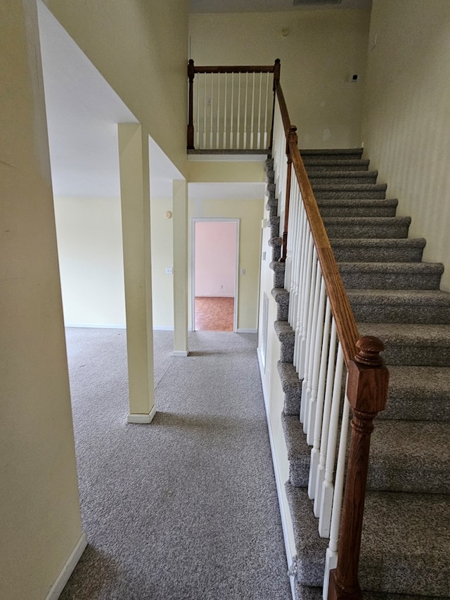 staircase with baseboards, carpet, and a high ceiling