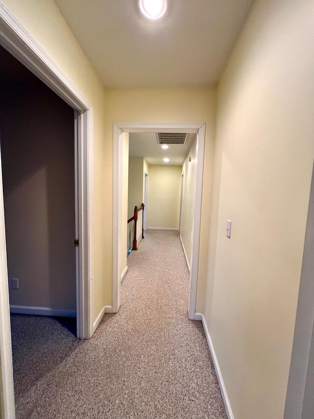 hall featuring an upstairs landing, carpet, visible vents, and baseboards