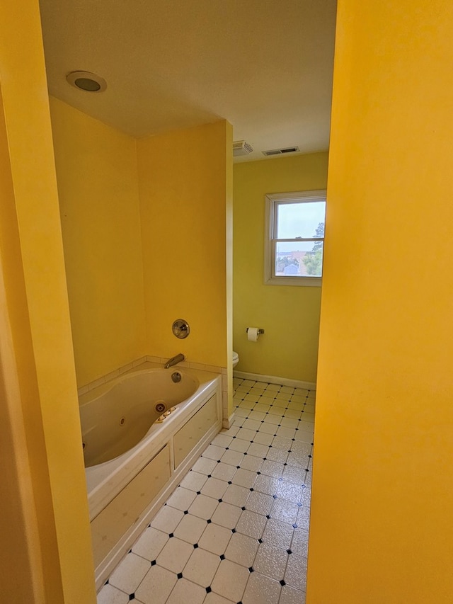 bathroom with visible vents, a jetted tub, baseboards, toilet, and tile patterned floors