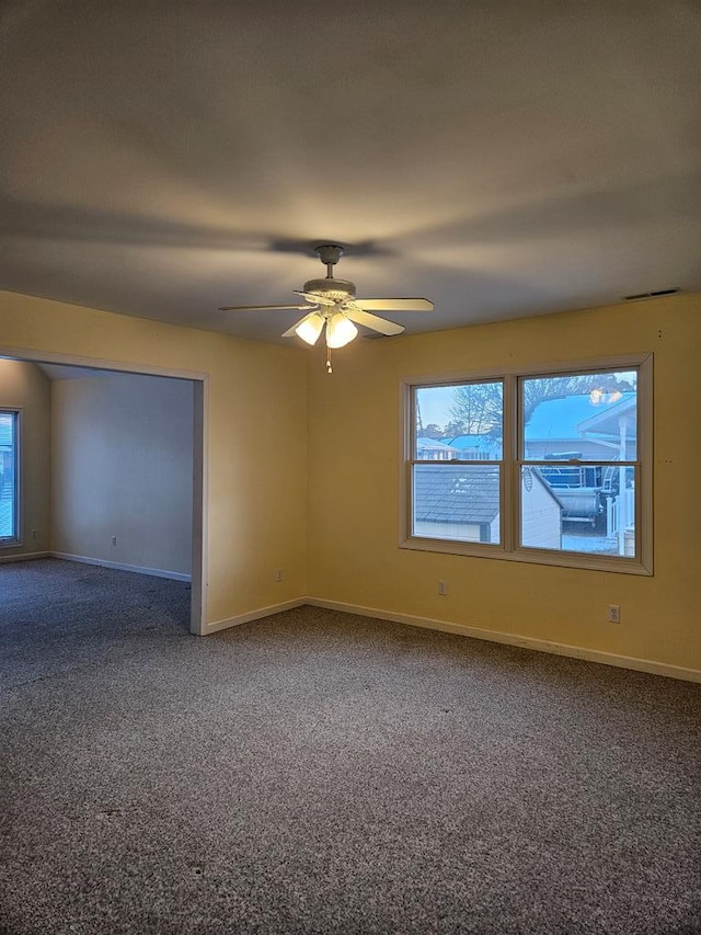 carpeted empty room with a ceiling fan and baseboards