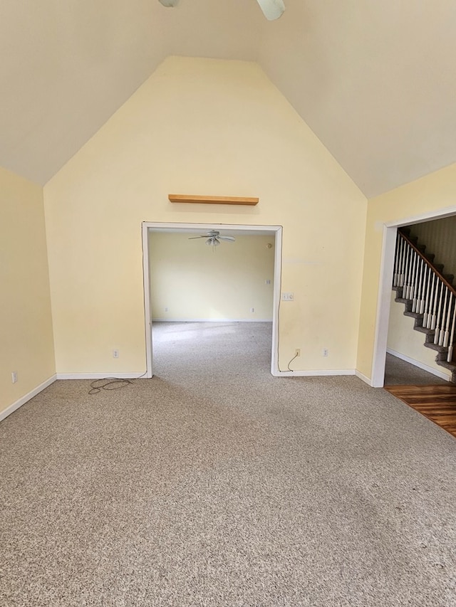 carpeted empty room featuring baseboards, stairway, high vaulted ceiling, and a ceiling fan