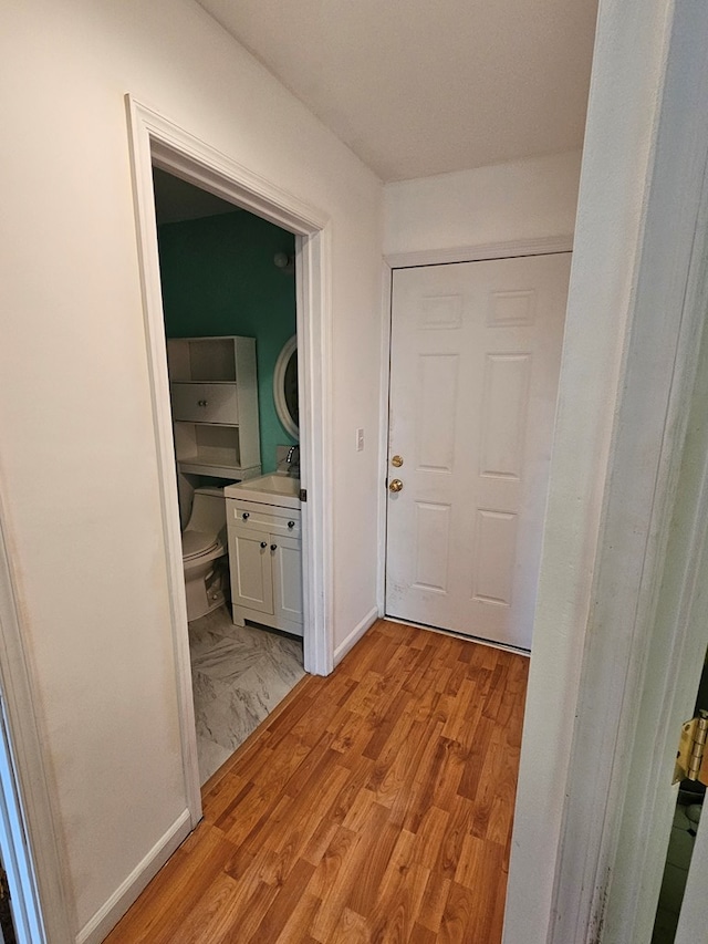 corridor featuring light wood-type flooring and baseboards