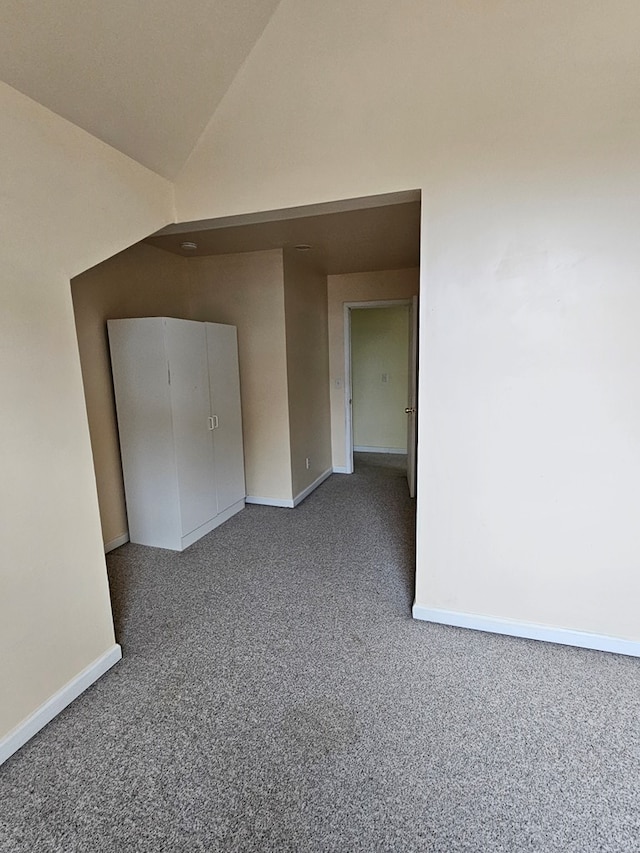 carpeted empty room with baseboards and lofted ceiling