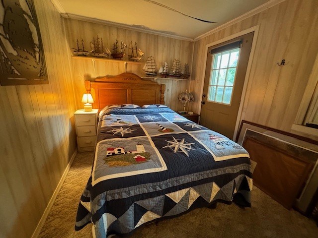 carpeted bedroom with ornamental molding and wooden walls