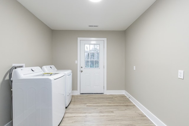 laundry room with washer and dryer and light wood-type flooring