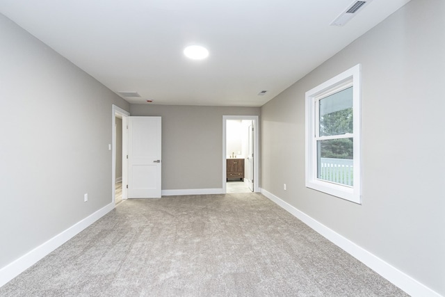 unfurnished bedroom with light colored carpet and ensuite bath