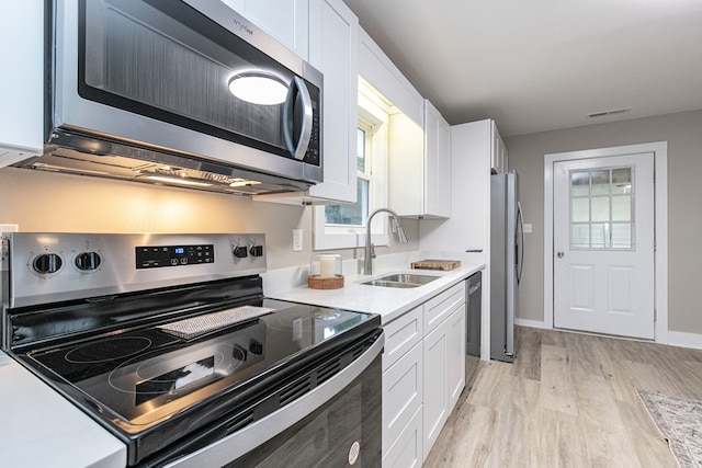 kitchen featuring sink, white cabinets, stainless steel appliances, and light wood-type flooring