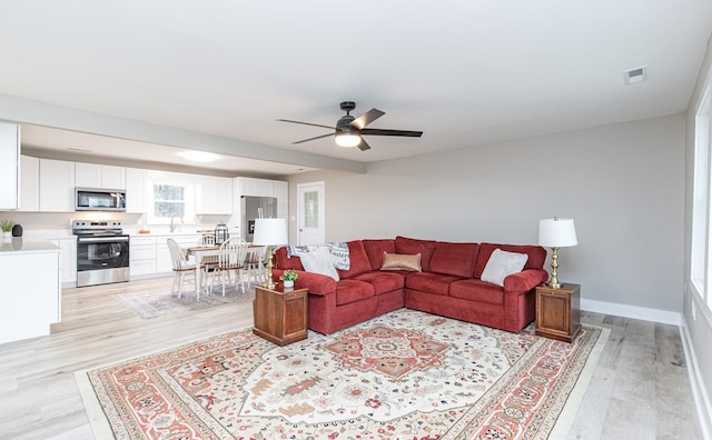 living room with ceiling fan, light wood-type flooring, and sink