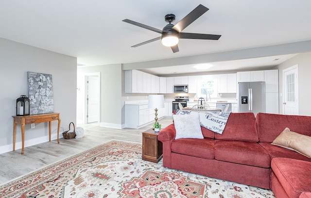 living room with ceiling fan, sink, and light hardwood / wood-style floors