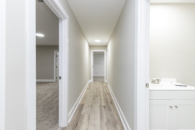 hallway with sink and light wood-type flooring