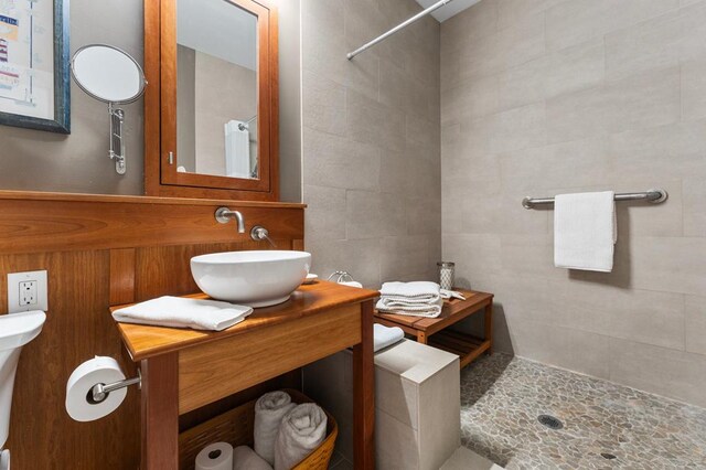 full bath with toilet, vanity, a tile shower, and tile walls