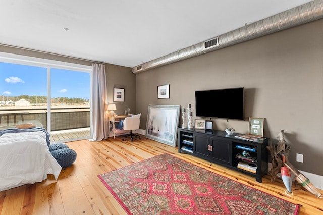 bedroom featuring access to outside, wood finished floors, and visible vents