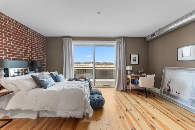 bedroom with access to exterior and wood finished floors