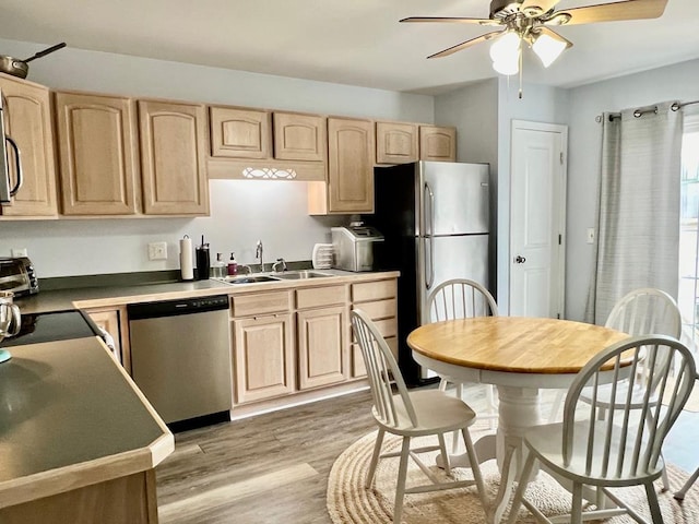 kitchen with stainless steel appliances, ceiling fan, sink, light brown cabinets, and light hardwood / wood-style flooring