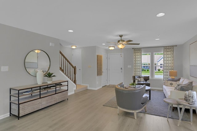 living area with recessed lighting, a ceiling fan, baseboards, stairs, and light wood finished floors