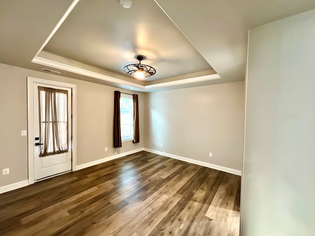 spare room featuring dark hardwood / wood-style flooring and a raised ceiling