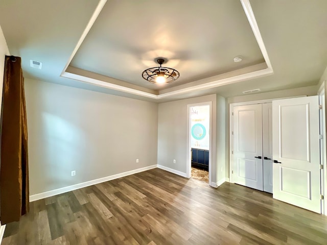 interior space with dark hardwood / wood-style flooring, a raised ceiling, and ensuite bath