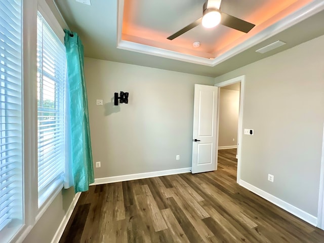 spare room with ceiling fan, a raised ceiling, and dark wood-type flooring