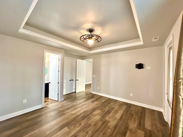 interior space with a tray ceiling and dark hardwood / wood-style floors