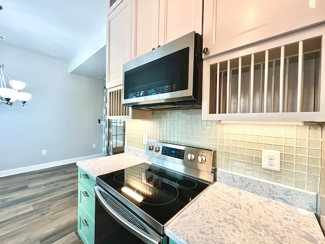 kitchen featuring appliances with stainless steel finishes, tasteful backsplash, light stone counters, a chandelier, and white cabinetry