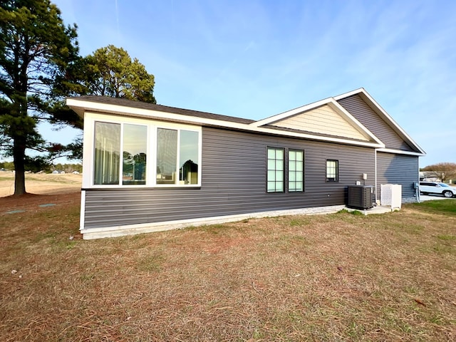 back of property featuring central AC and a lawn