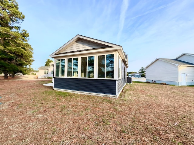 view of side of property with a sunroom, a yard, and central AC unit