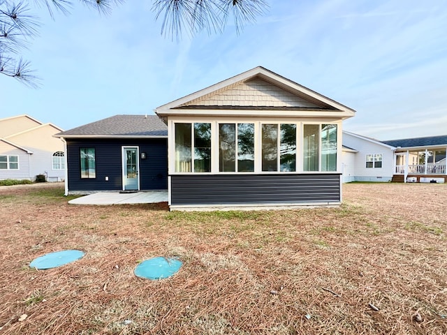 rear view of property with a sunroom, a yard, and a patio