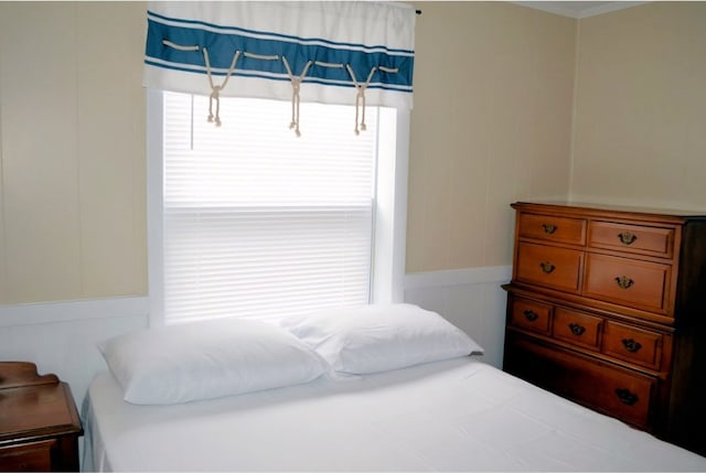 bedroom featuring multiple windows and a decorative wall