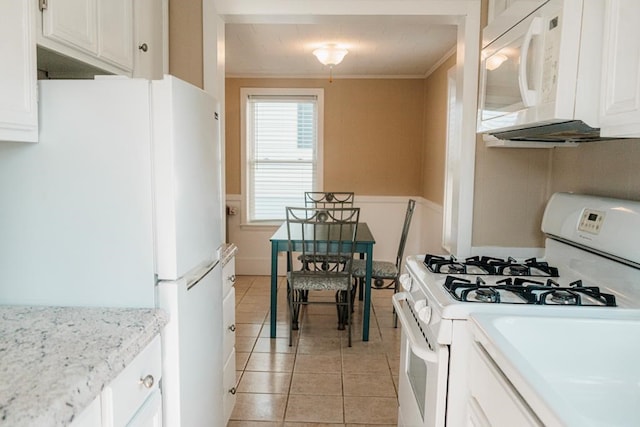 kitchen with white appliances, white cabinetry, crown molding, and light tile patterned flooring