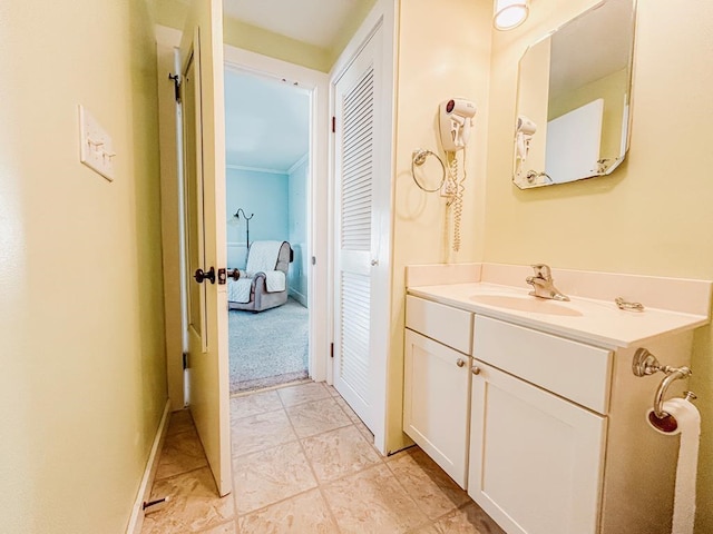 bathroom featuring baseboards, crown molding, and vanity