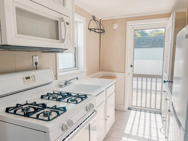 kitchen featuring white appliances, white cabinets, crown molding, a sink, and light tile patterned flooring