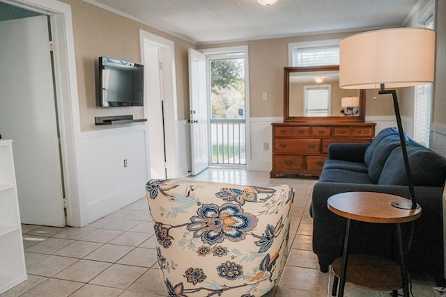 living room with a wainscoted wall, crown molding, and light tile patterned floors