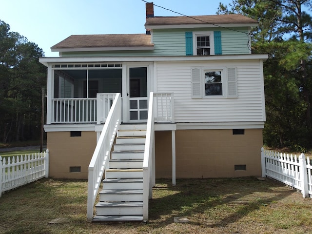 rear view of property with a lawn and a sunroom