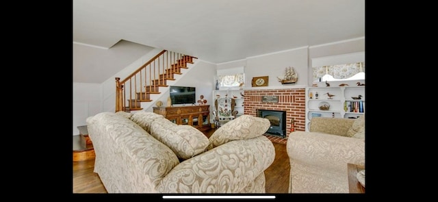 6346 Cropper St, Chincoteague, VA 23336 - living area featuring stairway, a brick fireplace, wood finished floors, and crown molding