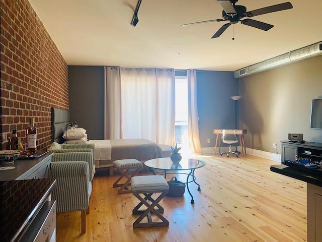 living room featuring ceiling fan, brick wall, hardwood / wood-style floors, and baseboards