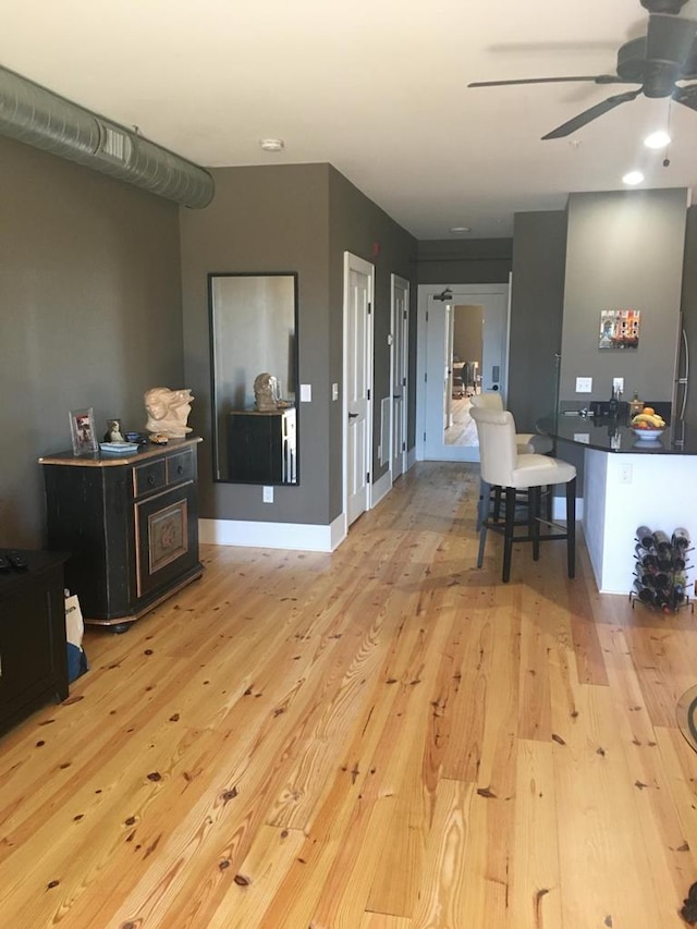 interior space with wood finished floors, a ceiling fan, and baseboards