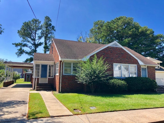 view of front facade featuring brick siding, a front yard, and an attached carport