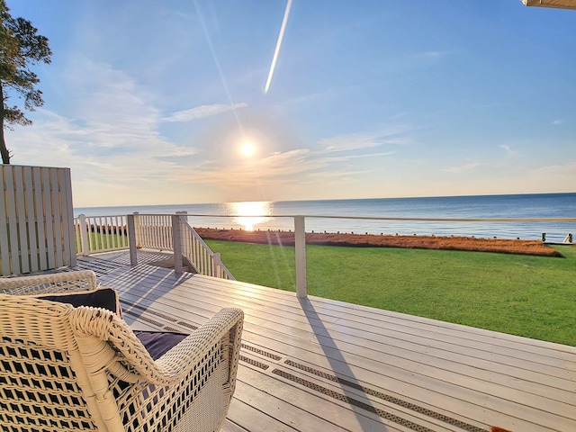 deck at dusk featuring a water view and a lawn