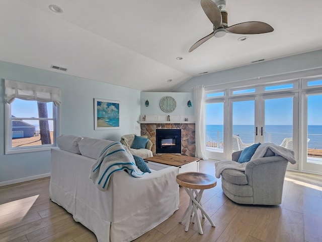 living room featuring a healthy amount of sunlight, light wood-type flooring, and a water view