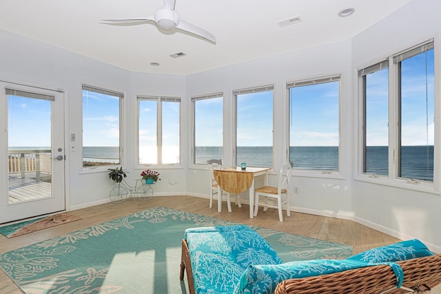 sunroom featuring ceiling fan, a water view, and visible vents