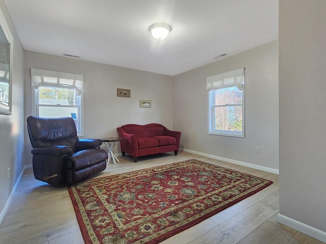 living area featuring hardwood / wood-style flooring, baseboards, and visible vents