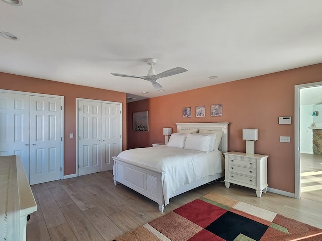 bedroom featuring ceiling fan, two closets, light wood-style flooring, and baseboards