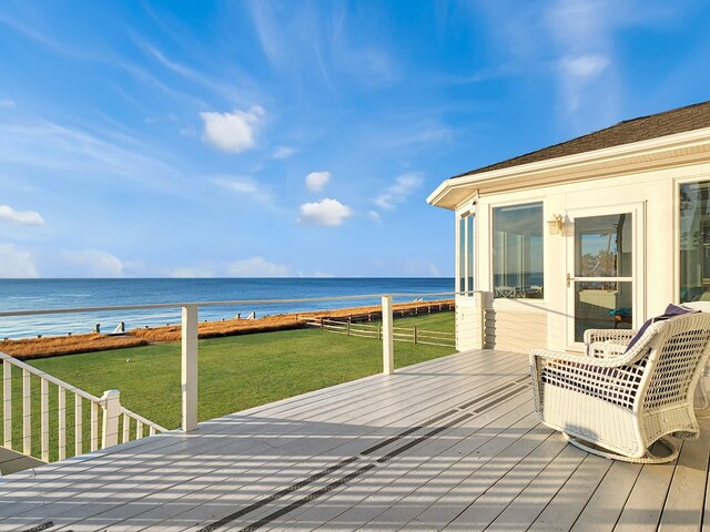 wooden terrace featuring a water view, a view of the beach, and a yard